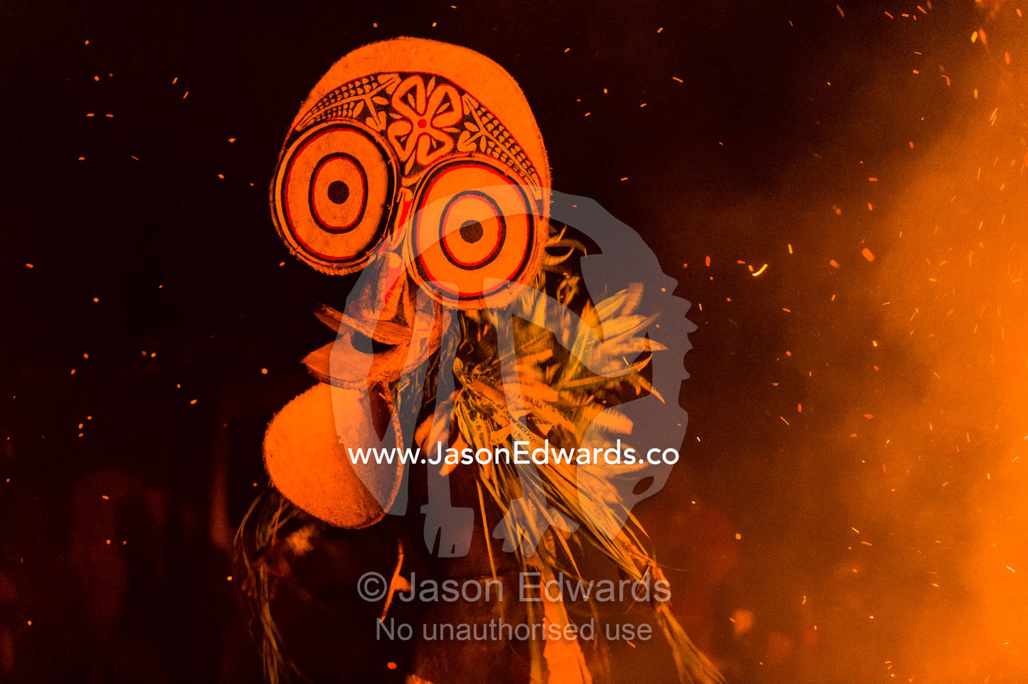 Baining warriors wearing grass and reed outfits and giant duck-like masks taunt the flames and their gods during a tribal fire ceremony. Rabaul, New Britain, Papua New Guinea
