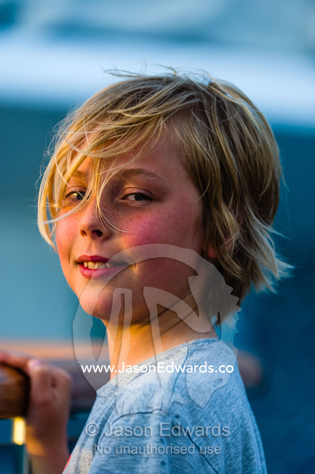 A blonde boy watches sunset from the deck of an expedition ship. Port Moresby, Gulf of Papua, Papuan Peninsula, National Capital District, Papua New Guinea