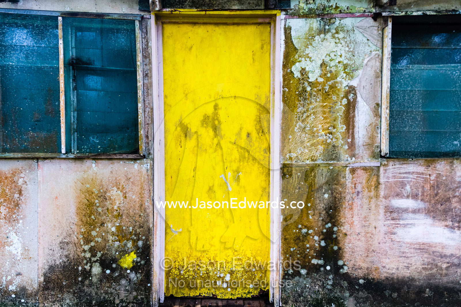 A bright yellow front door covered in mold on a tropical island. Samarai Island, Orangerie Bay, Milne Bay Province, Papua New Guinea