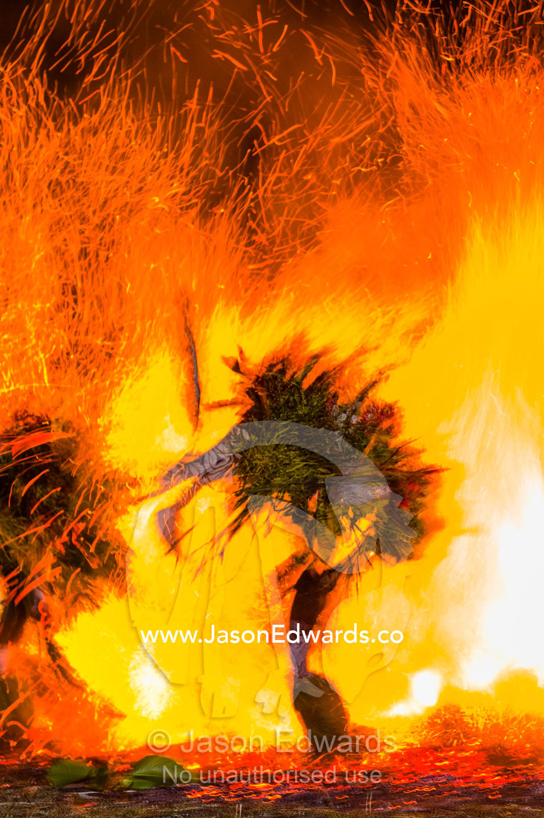 Baining warriors wearing grass and reed outfits and giant duck-like masks taunt the flames and their gods during a tribal fire ceremony. Rabaul, New Britain, Papua New Guinea