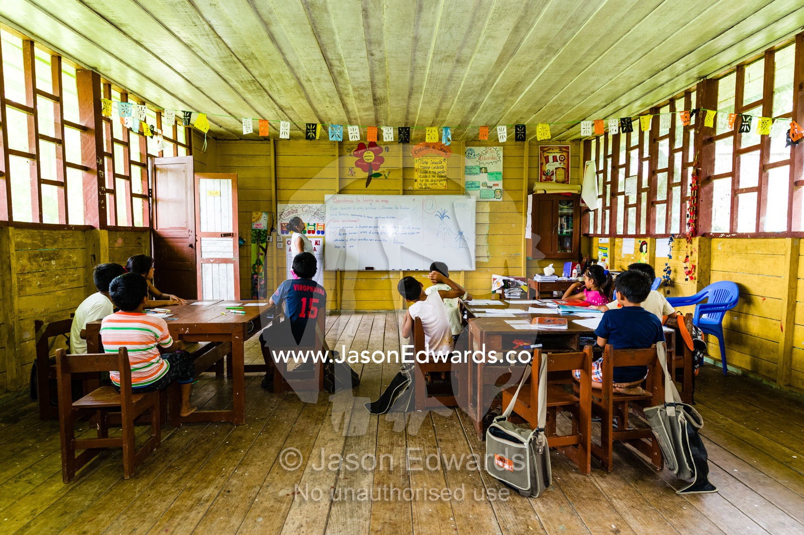 A teacher and her students in a school classroom in an Amazon village. Boca Pariamanu Native Community, Madre de Dios Region, Peru