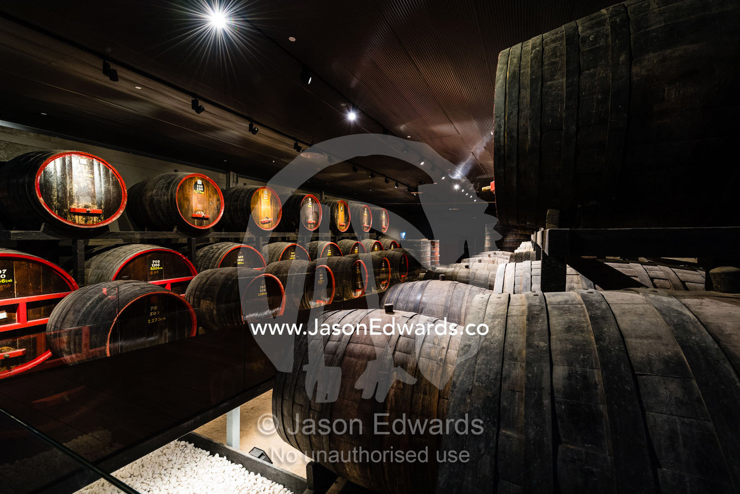 A row of wine barrels and vats stored in a climate controlled underground tunnel. Rosslyn Park, Adelaide, South Australia, Australia