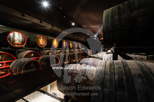 A row of wine barrels and vats stored in a climate controlled underground tunnel. Rosslyn Park, Adelaide, South Australia, Australia
