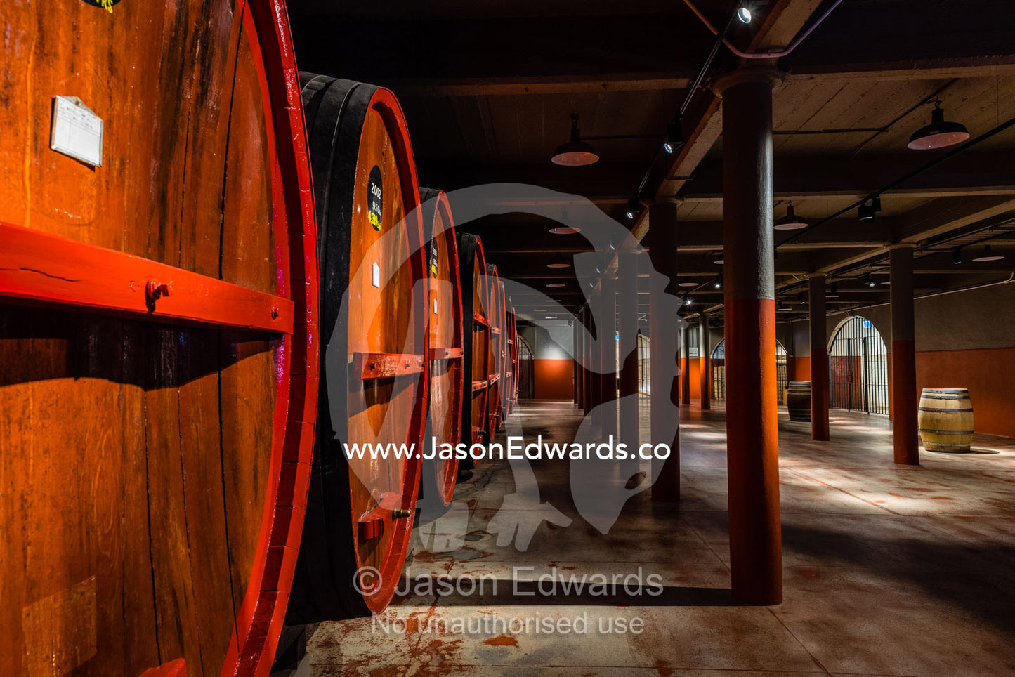 A row of wine barrels and vats stored in a climate controlled underground tunnel. Rosslyn Park, Adelaide, South Australia, Australia