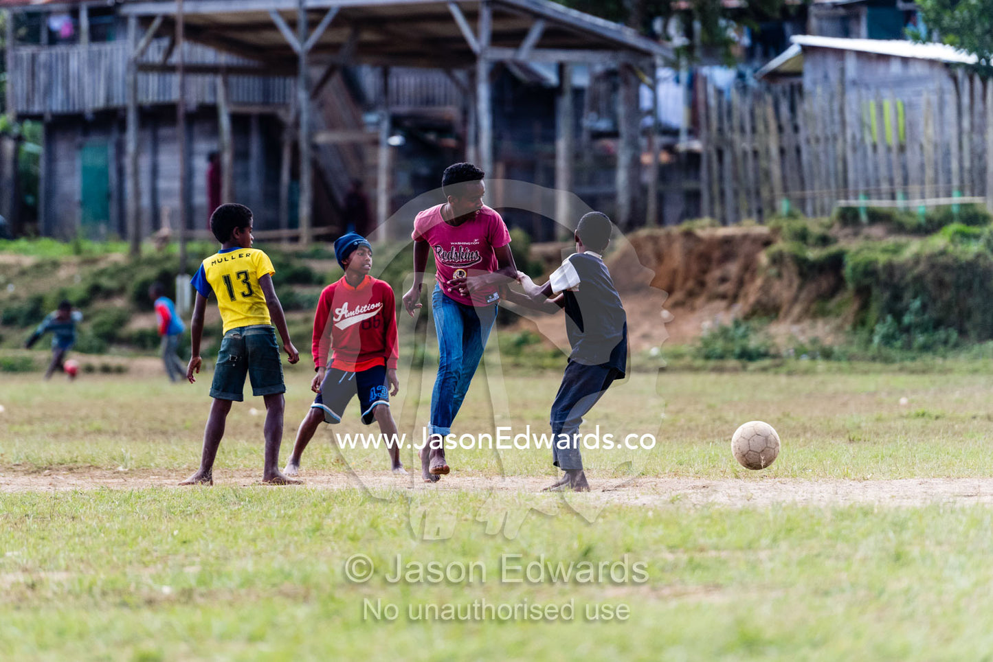 A group of boys playing football soccer in a village field. Andasibe, Madagascar