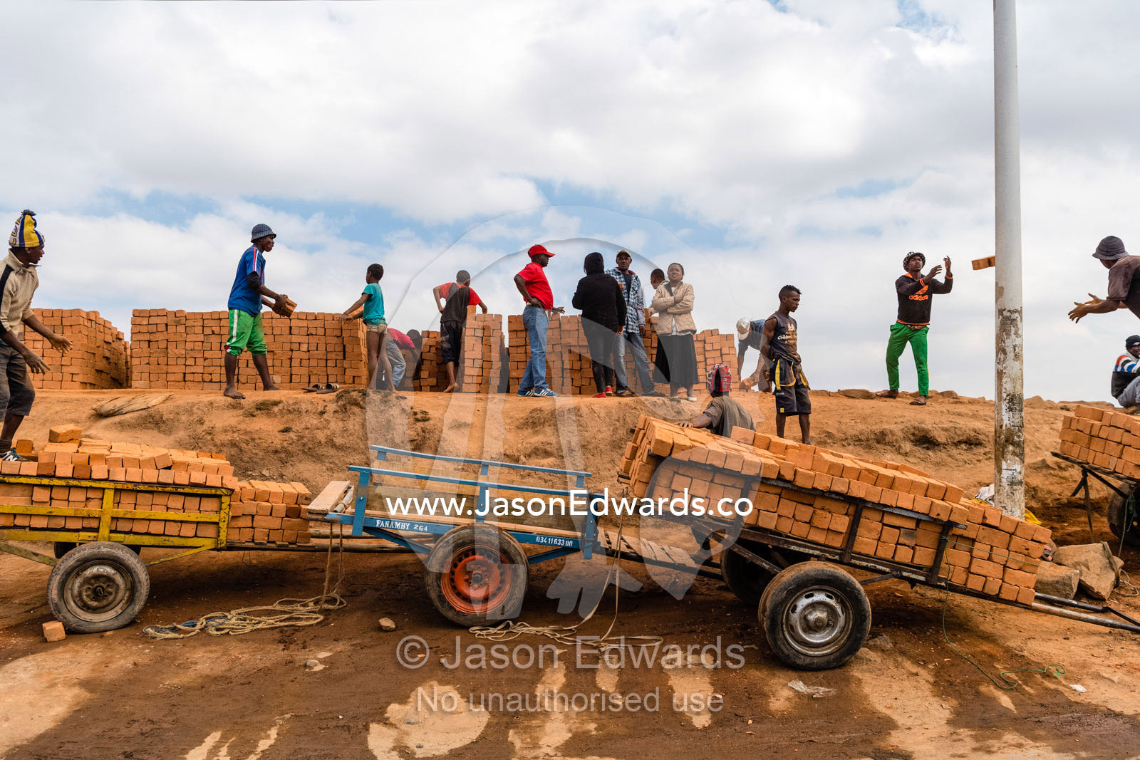 Men in a foundry loading handmade bricks onto trolleys for delivery for construction. Antananarivo, Madagascar