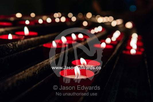 Prayer candle flames glowing in the darkness of a Catholic church. Lisbon, Lisboa, Portugal