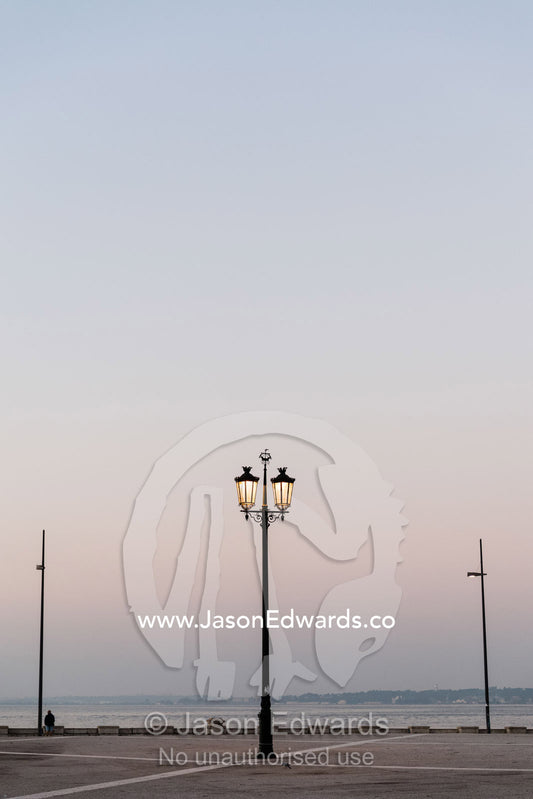 An ornate antique street lamp glowing in the pastel pre-dawn light. Lisbon, Lisboa, Portugal