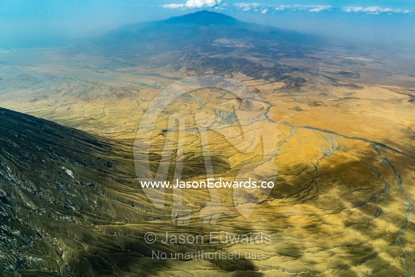 An aerial view of grass covered lava flows descending the slopes of an active volcano. Crater Highlands, Ngorongoro Hig, African Rift Valley , Serengeti National Park, Tanzania
