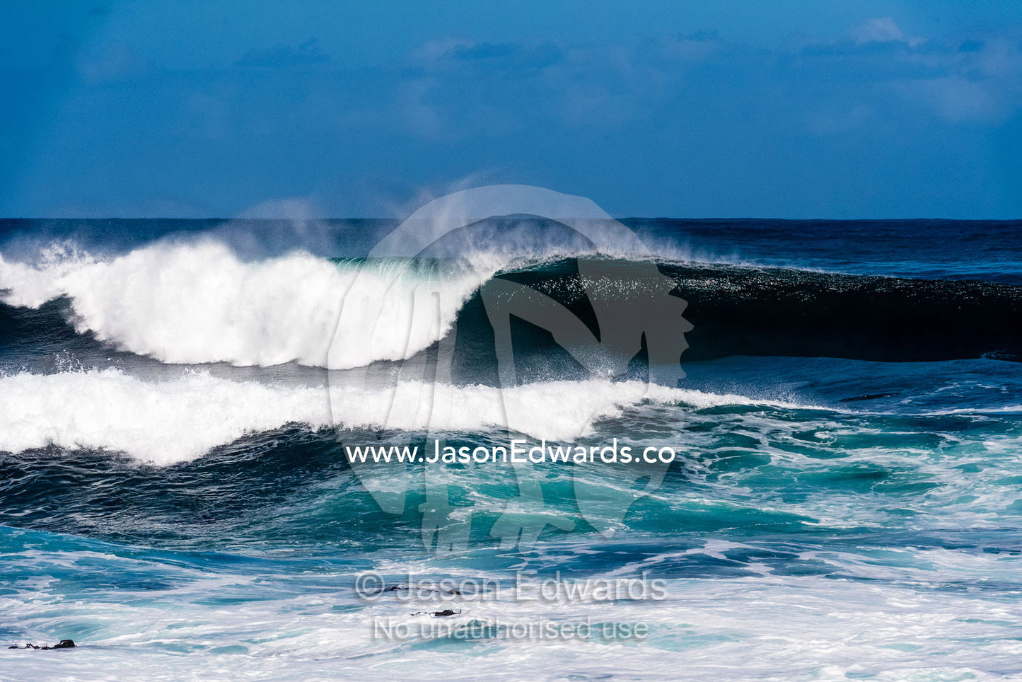A peeling ocean wave forms a barrel as it hits the shallows beneath a cliff. Cape Point National Park, South Africa