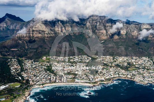 An aerial view of sprawling suburbs along a rugged mountainous coastline. Cape Point National Park, South Africa