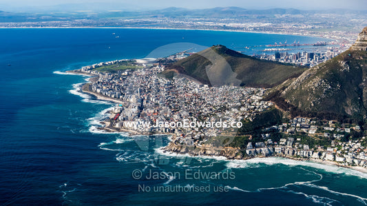An aerial view of sprawling suburbs along a rugged mountainous coastline. Cape Point National Park, South Africa