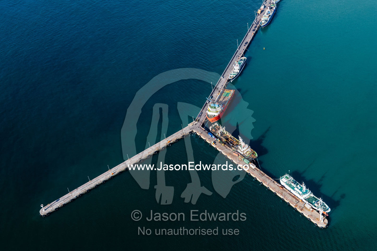 An aerial view of fishing trawlers moored at a concrete jetty in port. Cape Town, Western Cape, South Africa