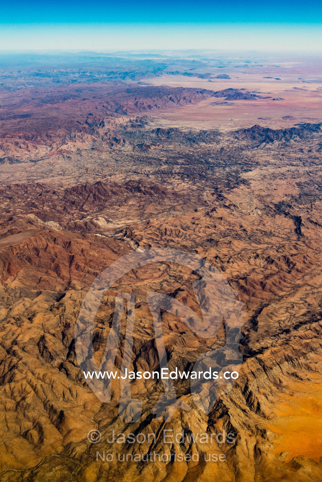 An aerial view of a vast baking desert mountain range with valleys carved by erosion. Walvis Bay, Namibia