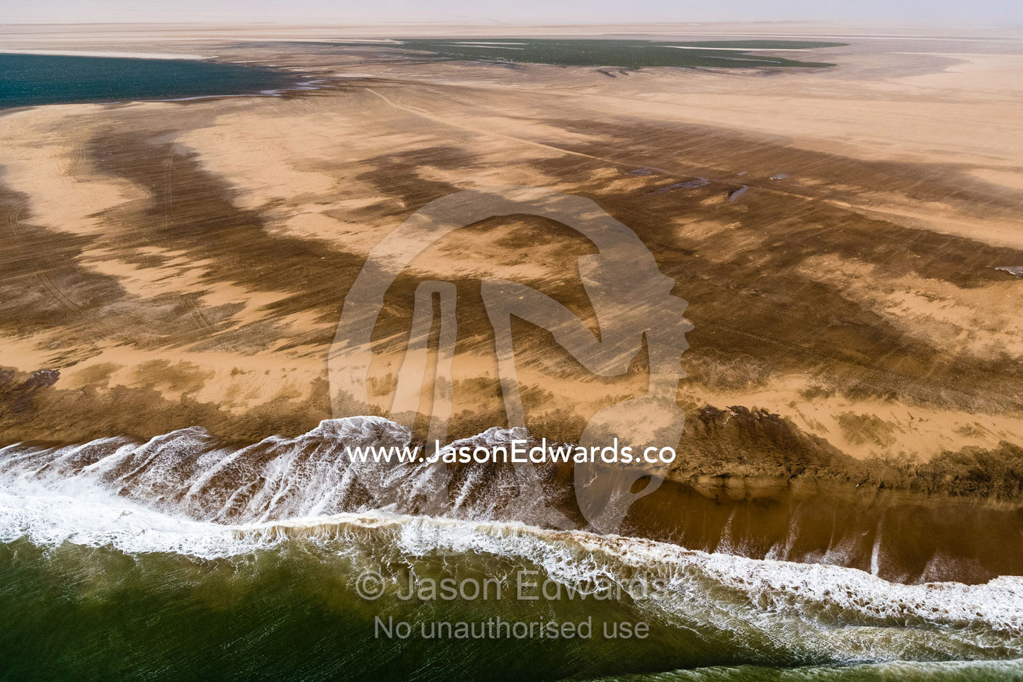 An aerial view of waves washing onto the beach of a remote and treacherous desert. Namib Desert, Diamond Coast, Skeleton Coast, Namib-Naukluft National Park, Namibia
