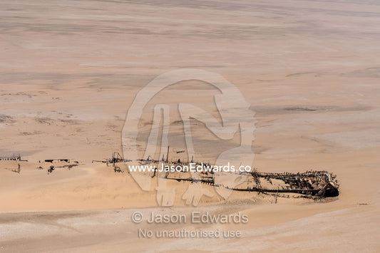 A shipwreck being consumed by the sands on the beach of a coastal desert. Namib-Naukluft National Park, Namibia