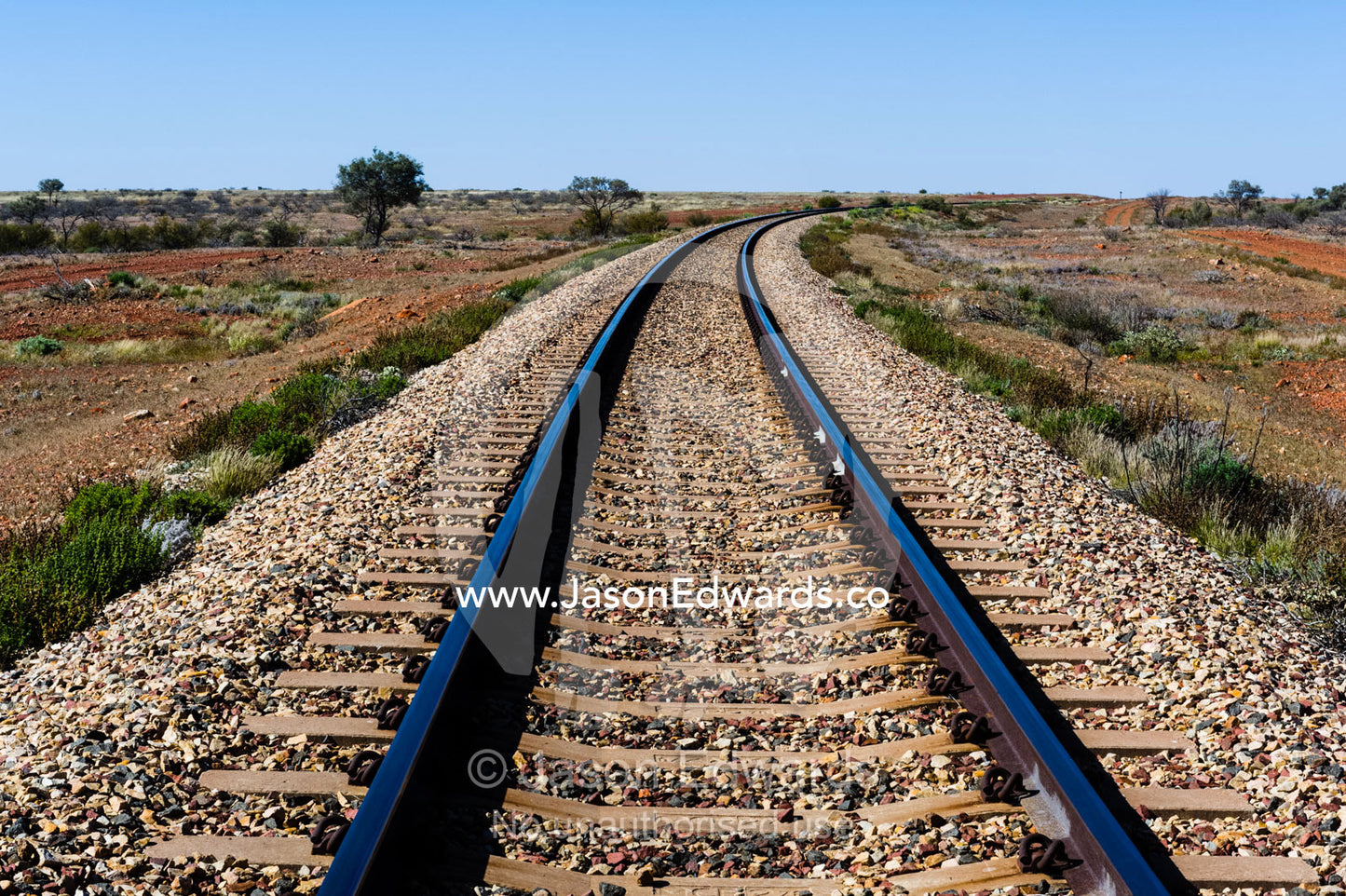 A railway line disappears across a desert plain in the outback. Coober Pedy, South Australia, Australia