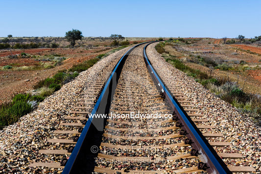 A railway line disappears across a desert plain in the outback. Coober Pedy, South Australia, Australia