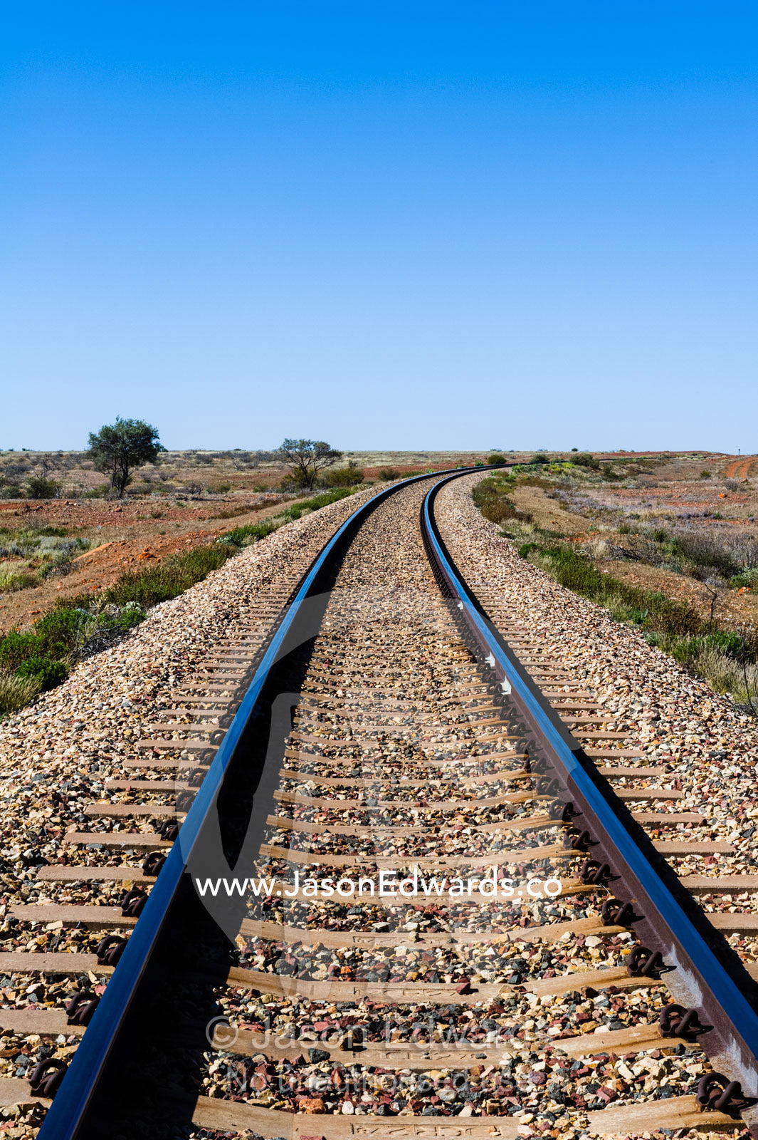 A railway line disappears across a desert plain in the outback. Coober Pedy, South Australia, Australia