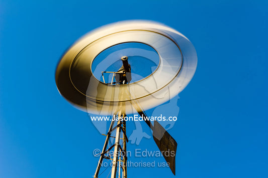 The blades of a windmill spinning in the wind on a remote outback cattle station in the desert. Coober Pedy, Wintinna Station, South Australia, Australia