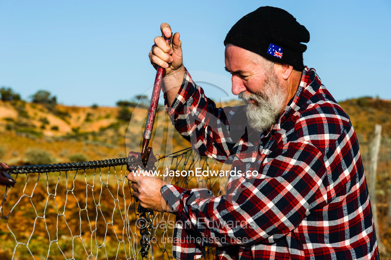 A patrol officer repairs the Dingo Fence or Dog Fence, a pest-exclusion fence built to keep dingoes away from sheep flocks. Coober Pedy, Dingo Fence, Dog Fence, South Australia, Australia