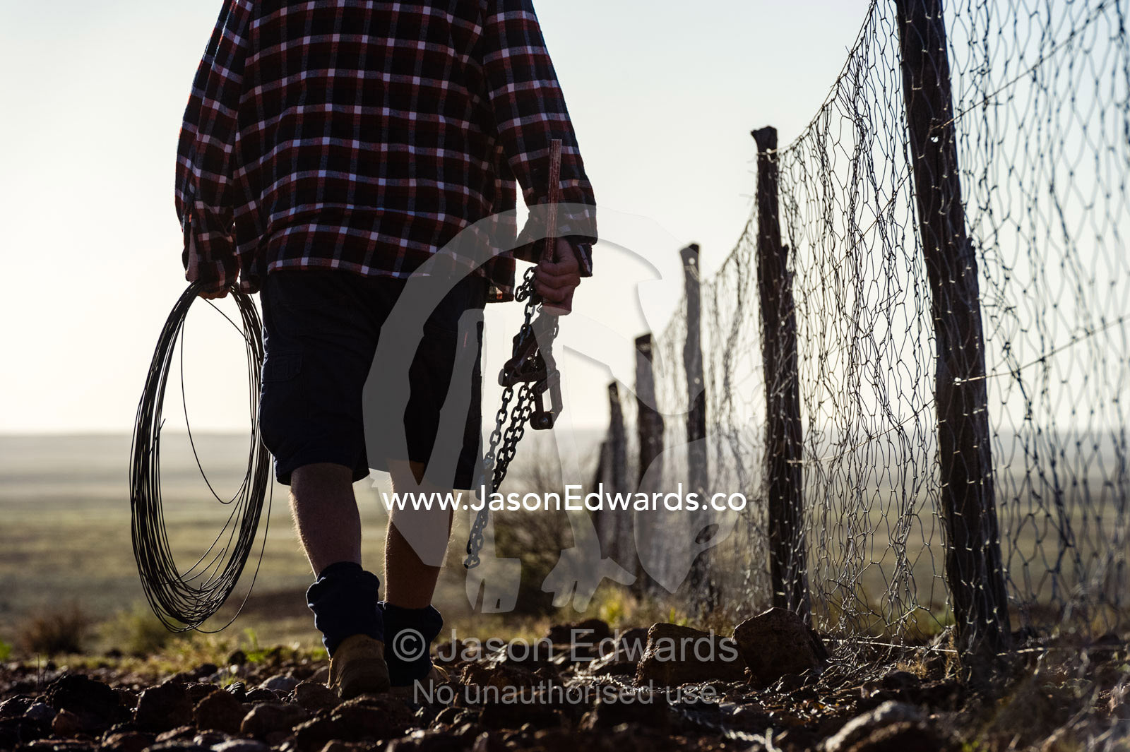 A patrol officer repairs the Dingo Fence or Dog Fence, a pest-exclusion fence built to keep dingoes away from sheep flocks. Coober Pedy, Dingo Fence, Dog Fence, South Australia, Australia