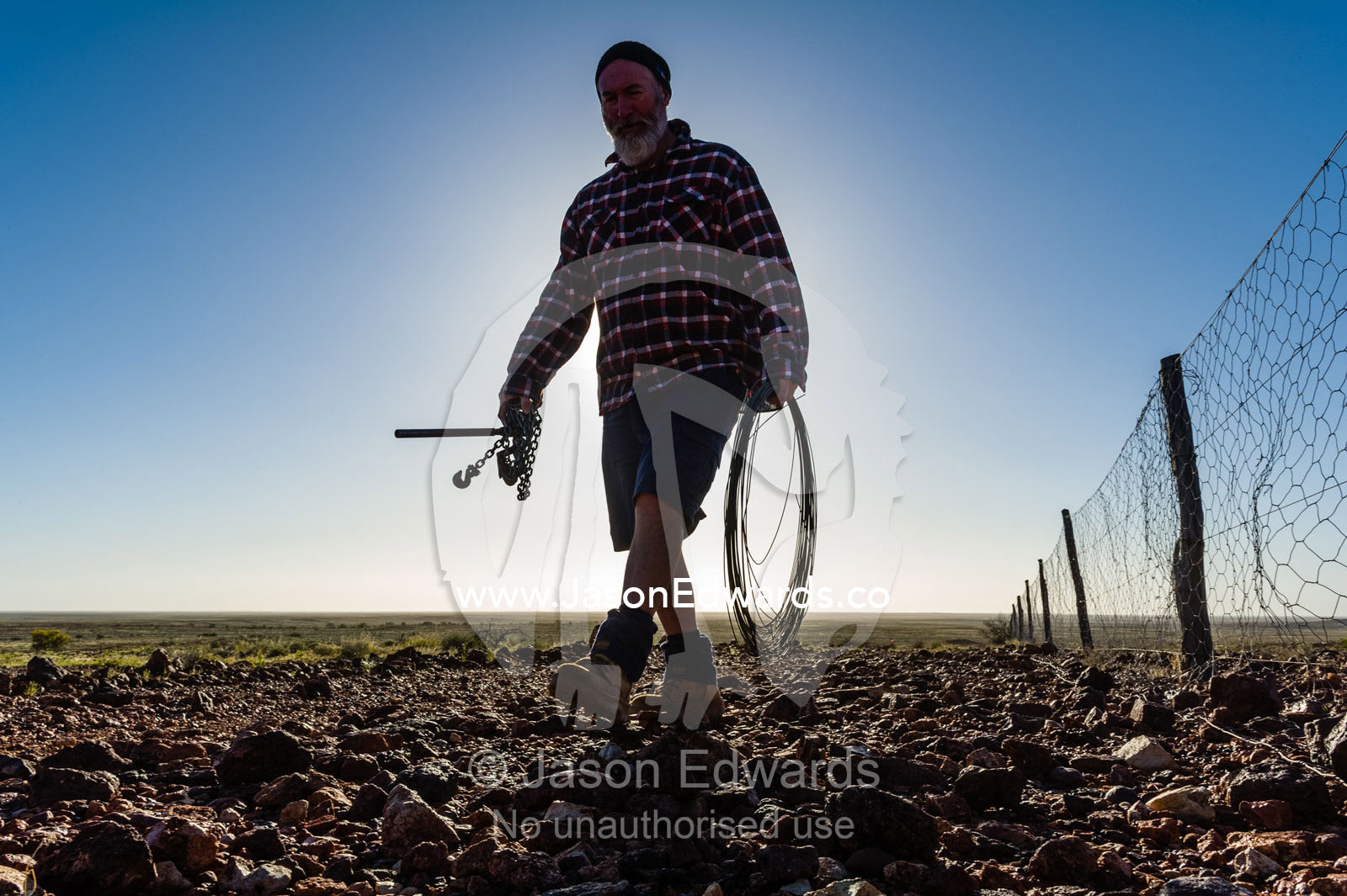 A patrol officer repairs the Dingo Fence or Dog Fence, a pest-exclusion fence built to keep dingoes away from sheep flocks. Coober Pedy, Dingo Fence, Dog Fence, South Australia, Australia