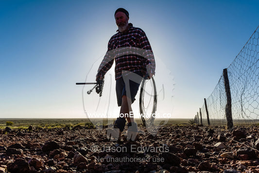 A patrol officer repairs the Dingo Fence or Dog Fence, a pest-exclusion fence built to keep dingoes away from sheep flocks. Coober Pedy, Dingo Fence, Dog Fence, South Australia, Australia