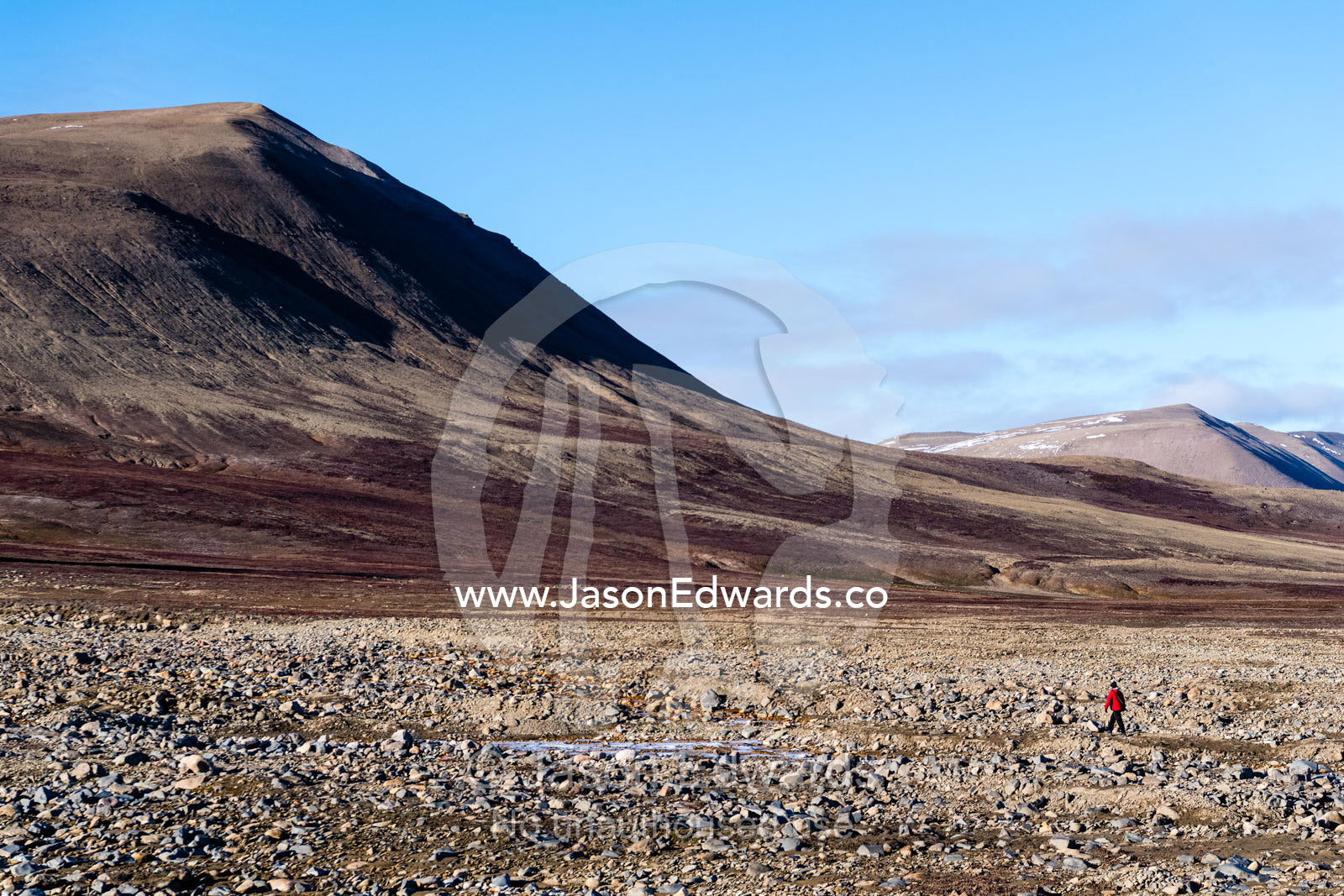 A solitary hiker explores a boulder plain in an arctic tundra valley. Scoresby Sound, Constable Point, Greenland
