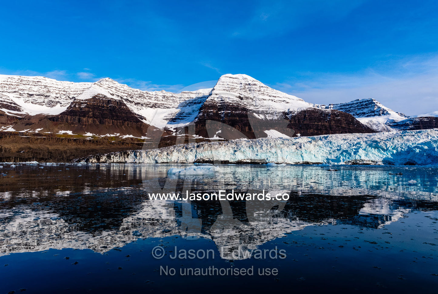 A glacier fracture zone and moraines reflecting in the still waters of an arctic fjord. Vikingbukt, Viking Bay, Brede Glacier, Scoresby Sound, Greenland