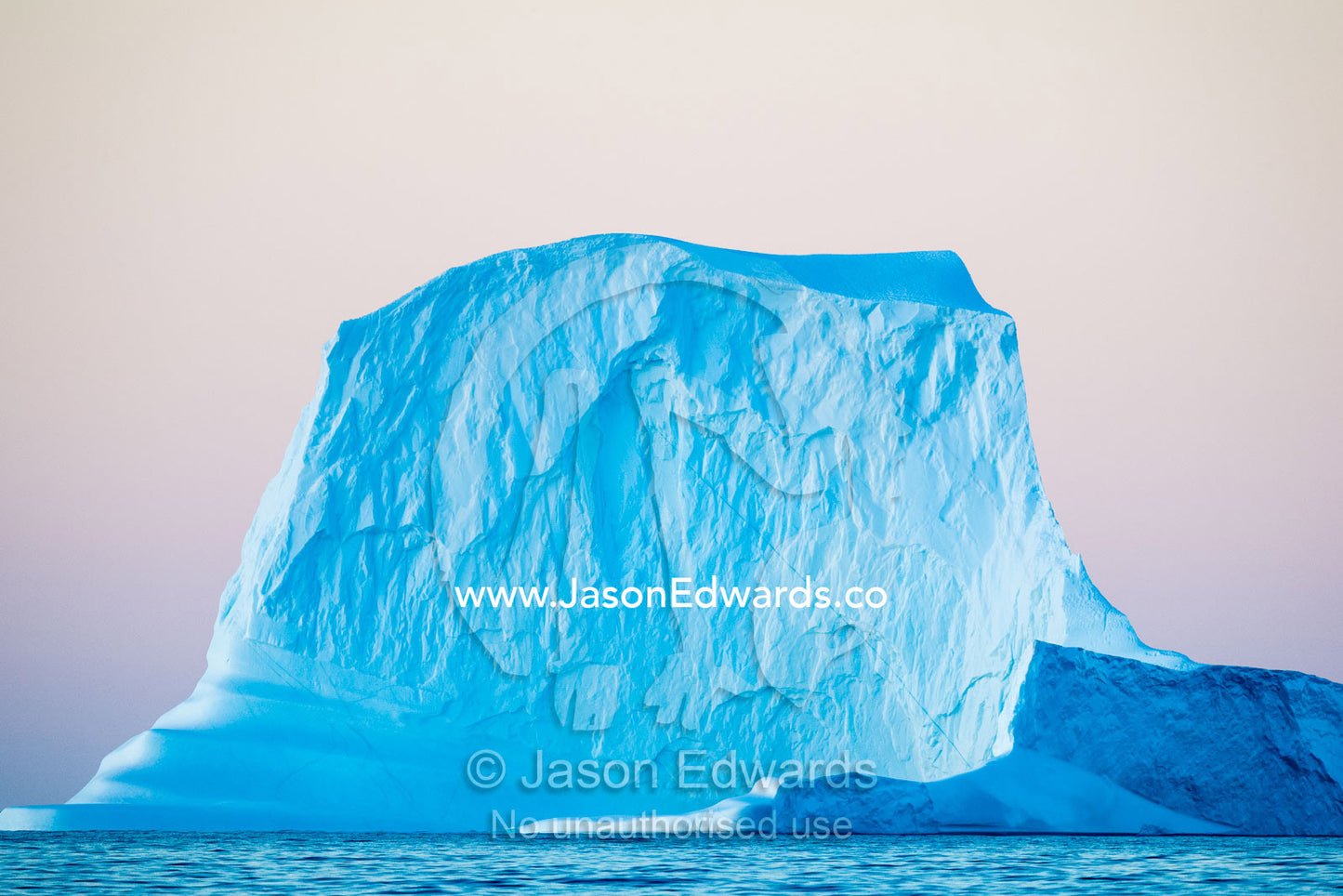 Late afternoon light falls across the surface of sheer iceberg cliffs floating in the arctic. Milne Land, Hall Bredning Fjord, Scoresby Sound, Greenland