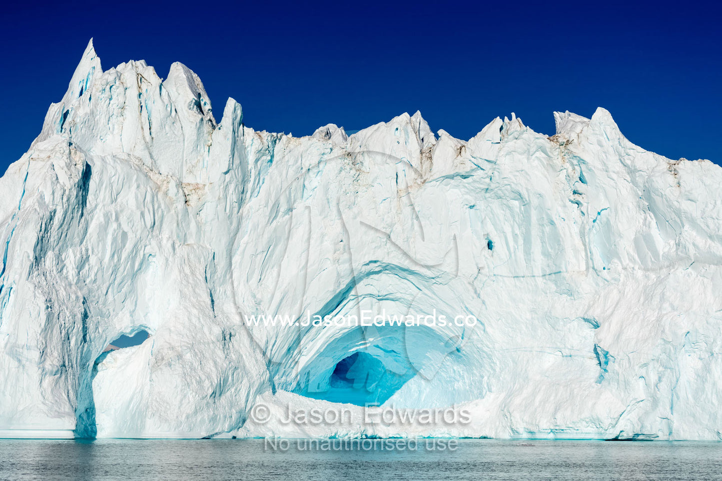 An ice cave caused by erosion carves it's way through the heart of an iceberg. Milne Land, Hall Bredning Fjord, Scoresby Sound, Greenland