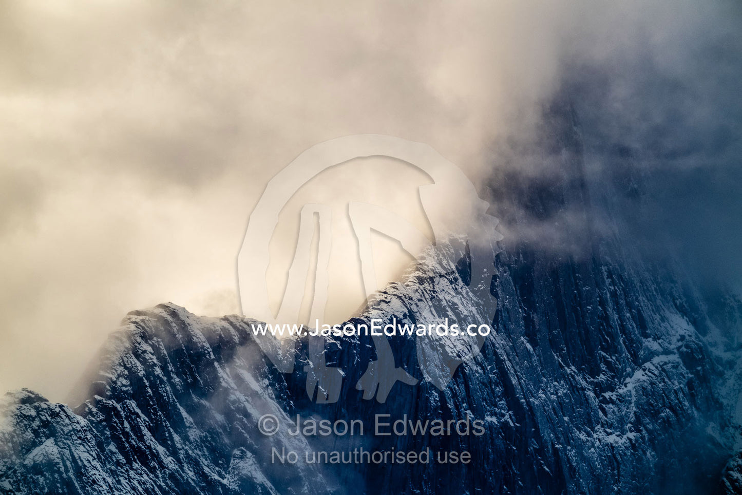 A storm consumes the sheer ridge line of an arctic mountain. Mudderbugt, Milne Land, Grundtvigskirken, Bjorne Islands, Scoresby Sound, Greenland