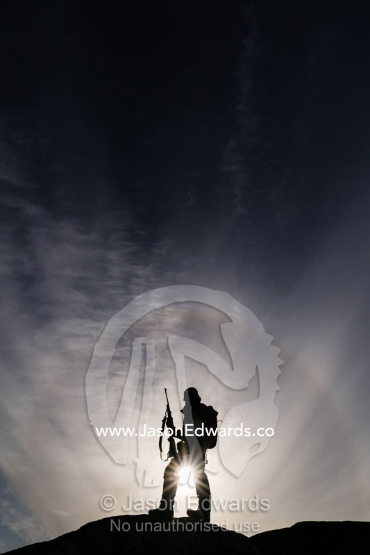 An arctic guide silhouette on a mountain top with a hunting rifle surrounded by a halo. Milne Land, Jytte Havn, Bjorne Islands, Scoresby Sound, Greenland