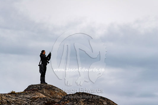 A hiker takes a photograph from a mountain top in the arctic. O Fjord, Island Fjord, Milne Lan, Bjorne Islands, Scoresby Sound, Greenland