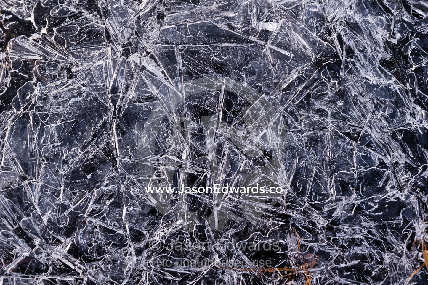 A mosaic of frozen ice crystals create geometric patterns on the surface of a freshwater stream in the arctic tundra. Scoresby Sound, Greenland