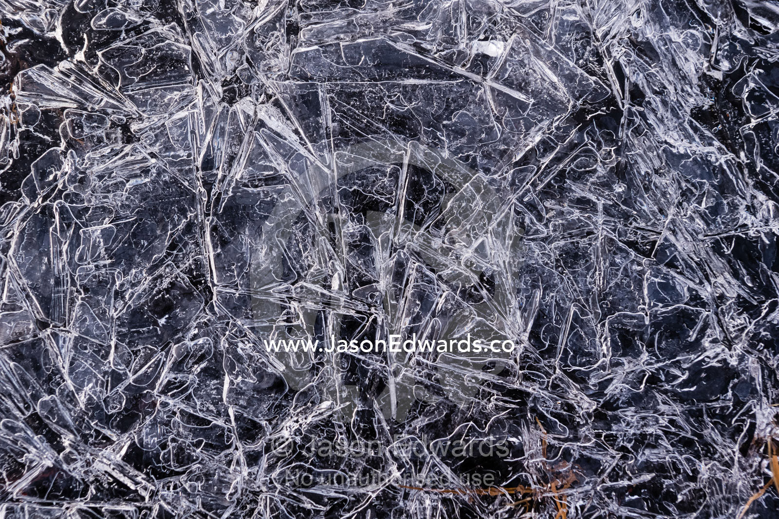 A mosaic of frozen ice crystals create geometric patterns on the surface of a freshwater stream in the arctic tundra. Scoresby Sound, Greenland