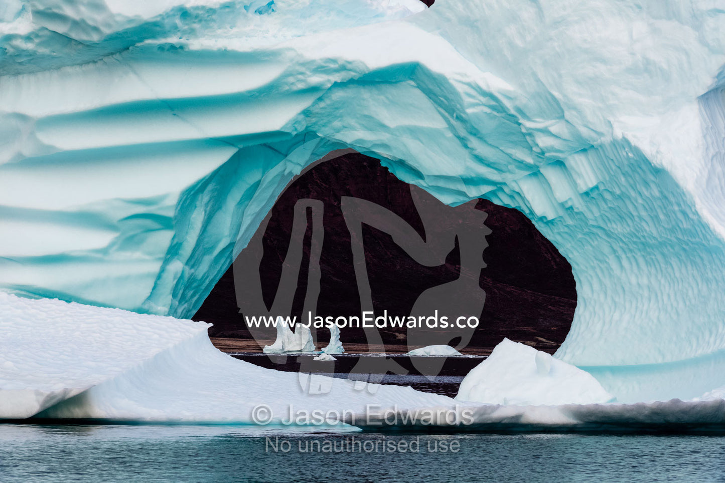 An erosion tunnel carved through an iceberg in an arctic fjord. Renland, Milne Land, Harefjord, Hare Fjord, Rype Fjor, Scoresby Sound, Greenland
