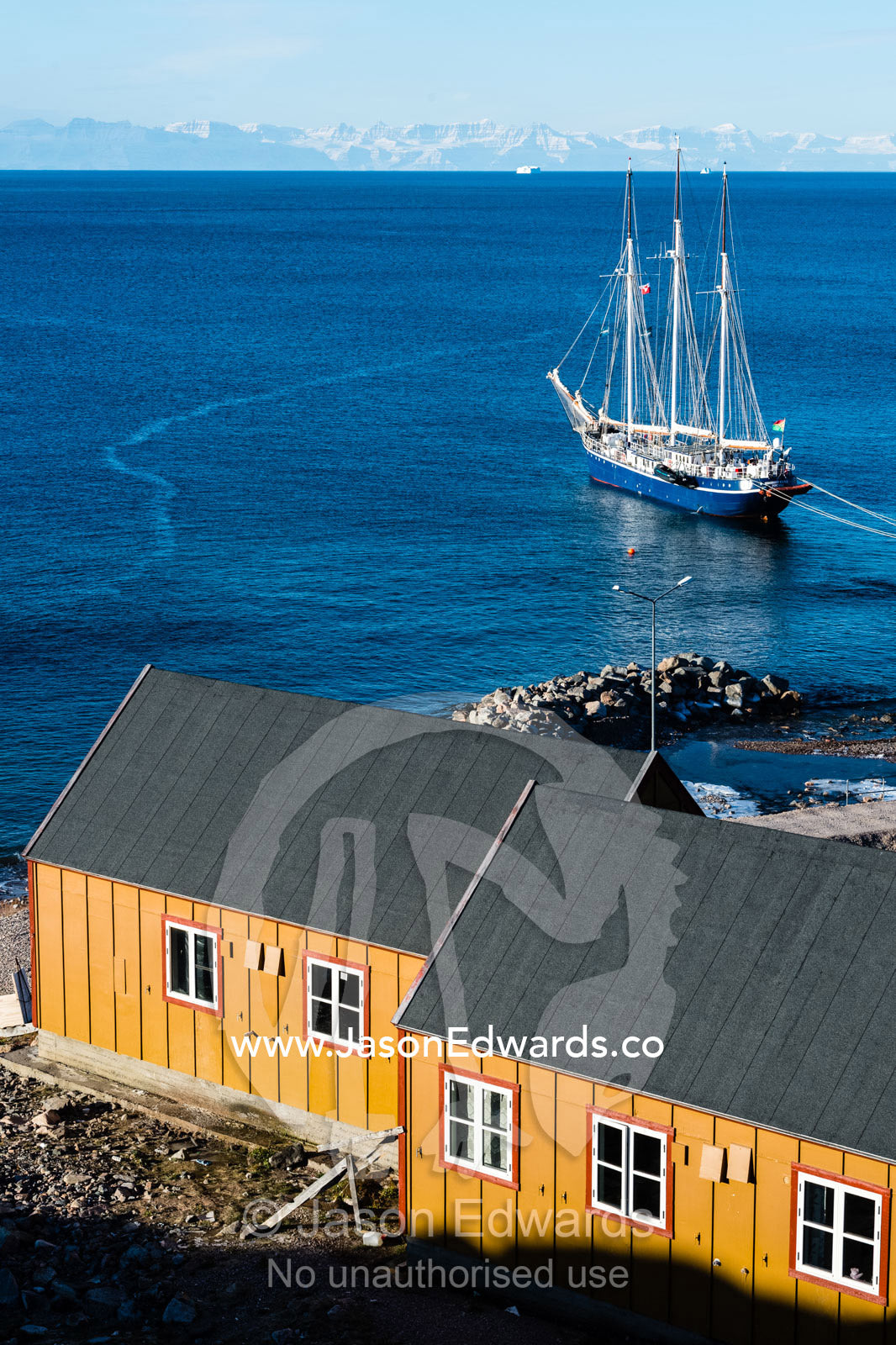 A Tall Ship Schooner moored in a safe harbour in an arctic inuit village. Sermersooq Municipality, Ittoqqottoormiit, Scoresby Sound, Greenland