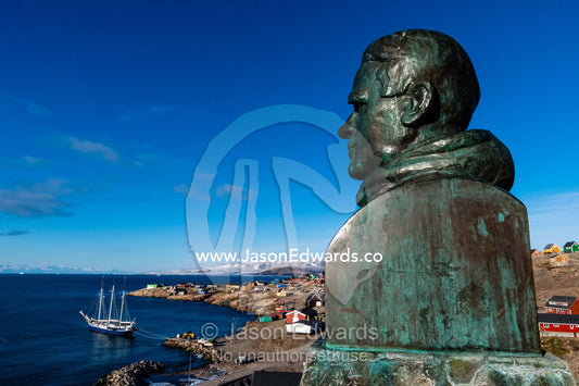 A bronze bust statue of Ejnar Mikkelsen overlooks the harbour of an inuit village. Sermersooq Municipality, Ittoqqottoormiit, Scoresby Sound, Greenland