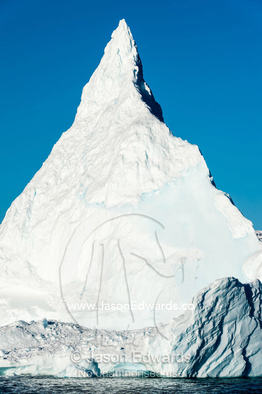 A pyramid spire of ice rises above the ocean from an iceberg. Milne Land, Hall Bredning Fjord, Scoresby Sound, Greenland