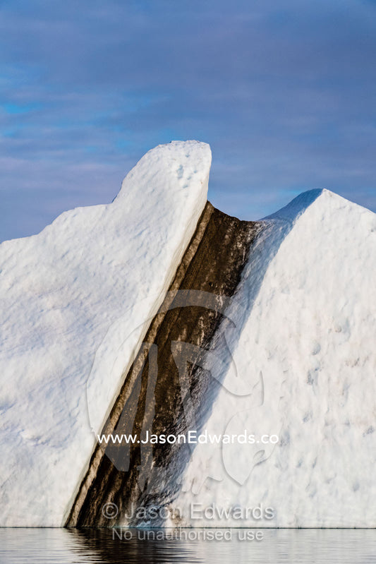Soil trapped in an iceberg absorbs heat and accelerates ice melting. Renland, Milne Land, Harefjord, Hare Fjord, Rype Fjor, Scoresby Sound, Greenland