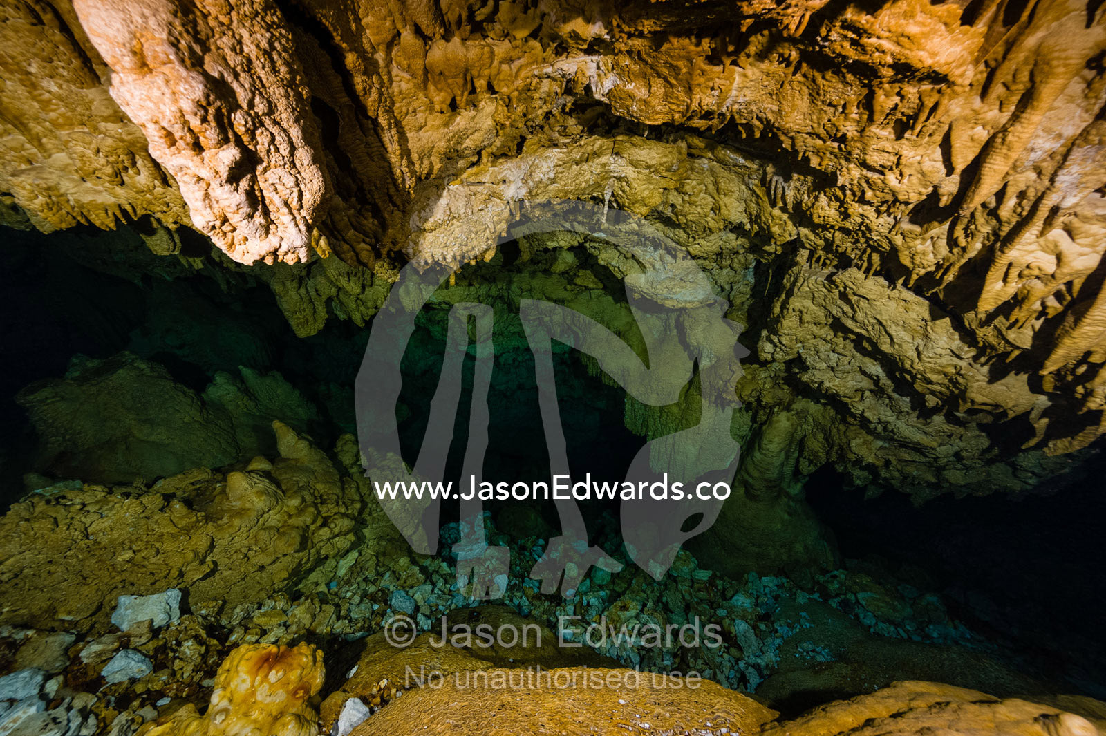 Limestone stalactites hanging from the ceiling in a submerged cave lead into a cavern tunnel. Makatea Atoll, Tuamotu Archipelago, French Polynesia