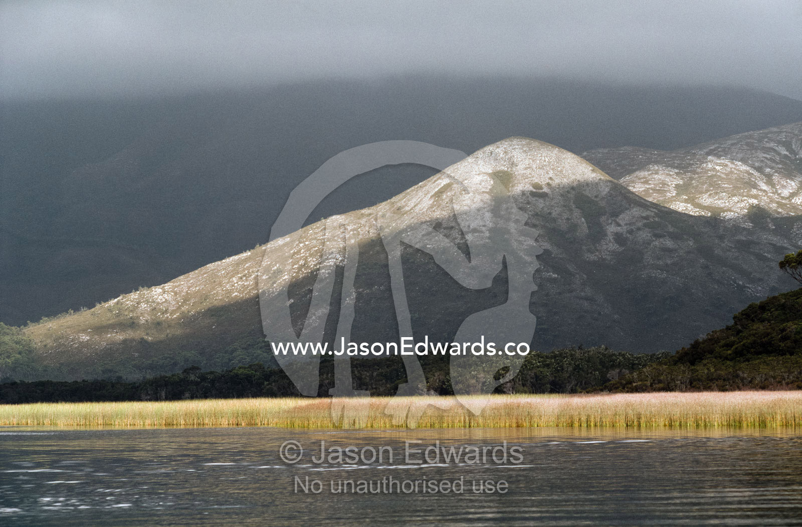Granite-topped mountains loom over Bathurst Harbour. Bathurst Harbour, Southwest National Park, Tasmania, Australia.