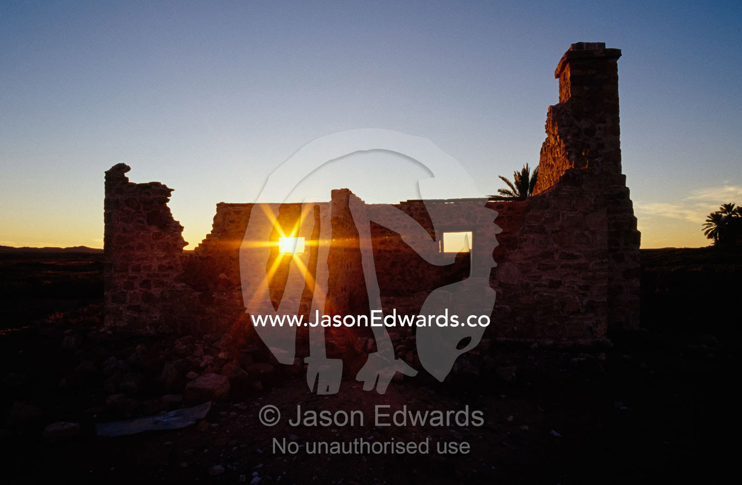 The setting sun shines through a window of an abandoned farmhouse. Dalhousie Springs, South Australia, Australia.