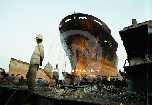 Workers and an old ship they are breaking up for steel reclaimation. Alang, India.