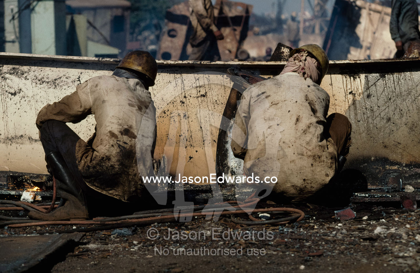 A pair of cutter squat over their torches in the blistering heat. Alang, India.