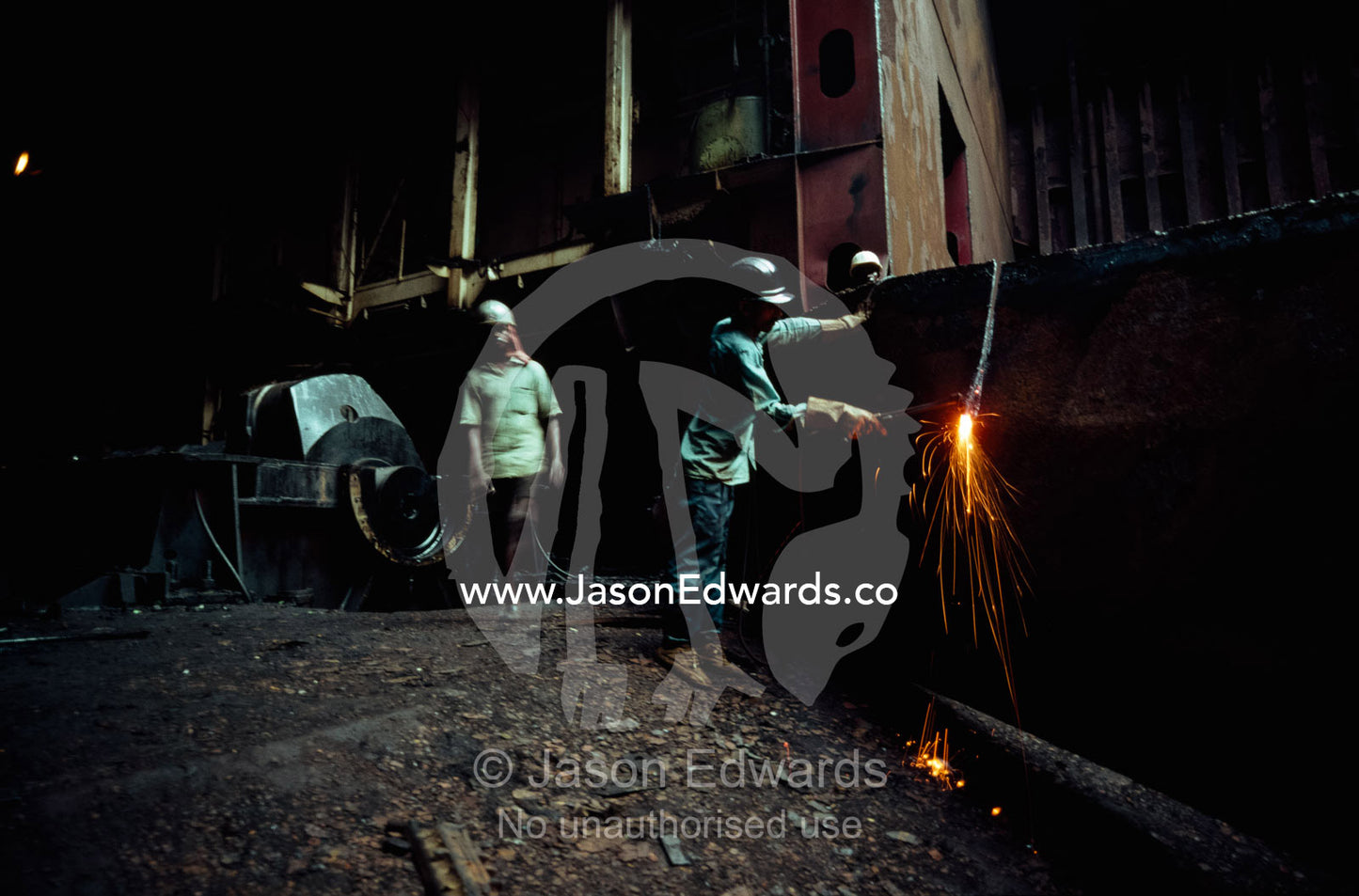Without eye protection, a worker uses a torch to dismantle a ship. Alang, India.
