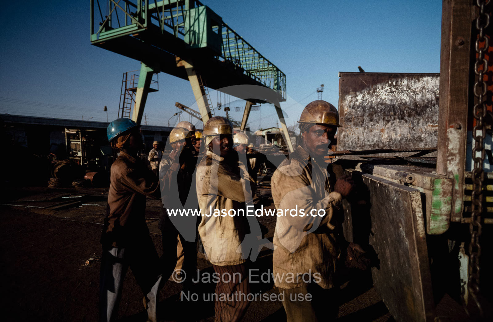 Laborers load sections of steel onto a truck to be sold as scrap. Alang, India.