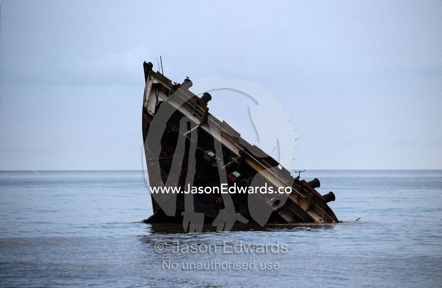 The stern of a dismantled ship emerges from the sea. Alang, India.
